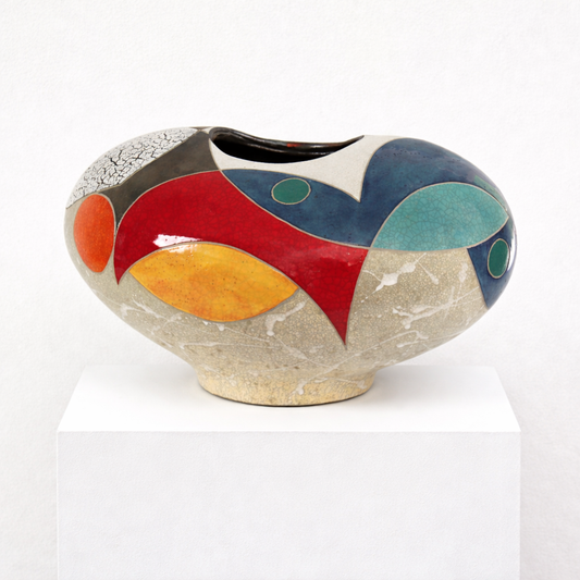 Change of Mind Vessel – wide low studio raku ceramic vessel by Gustavson with sandy crackled ground and bold arcing planes of red, deep navy, teal, and warm yellow, small teal and green circles as recurring mark, two sides reading differently