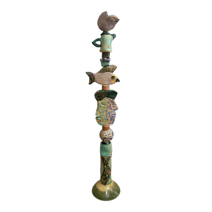Juxtaposition 2 Ceramic Totem – hand-built ceramic totem by Zimmerman with small bird at top, large fish spreading wide in purple, gold, and black stripes, teal and purple geometric face below, bold black and gold abstract base marks from printmaking vocabulary