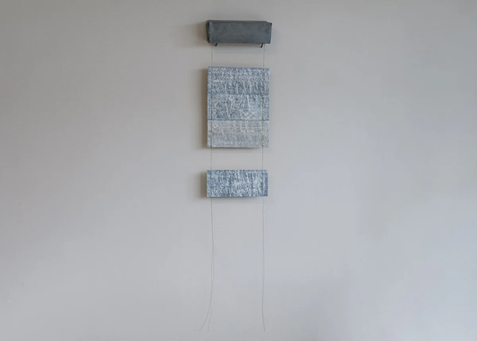 Untitled 5 – suspended textile installation by Terese Garcia with two small grey densely worked panels hanging from a single horizontal bar by fine threads, the gap between them as much part of the work as the panels